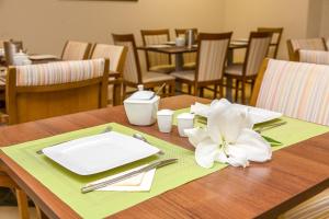 a wooden table with a plate and a flower on it at Willa Biala Lilia Old Town in Gdańsk