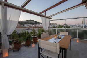 einen Holztisch und Stühle auf dem Balkon in der Unterkunft Acropolis at your fingertips in Athen