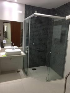 uma casa de banho com um lavatório e uma cabina de duche em vidro. em Pousada la Portella em Cabo Frio