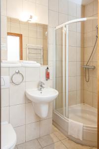 a white bathroom with a sink and a shower at Willa Biala Lilia Old Town in Gdańsk