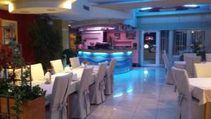 um restaurante com mesas e cadeiras brancas e um bar em Apartments Silvana em Trogir