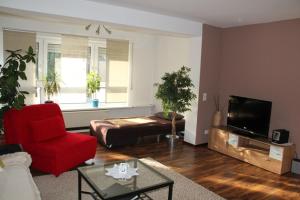 uma sala de estar com uma cadeira vermelha e uma televisão em Ferienwohnung Im Liestengarten em Auggen