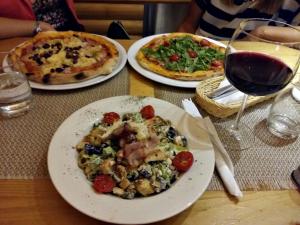 una mesa con tres platos de comida y una copa de vino en Guest House Nokturno, en Zagreb