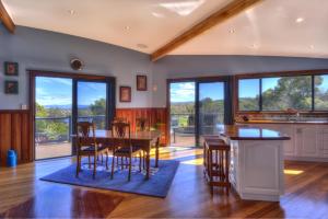 a dining room with a table and chairs and windows at Mayakitana ~ Overlooking the golf course in Coles Bay