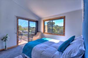 a bedroom with a bed and a large window at Mayakitana ~ Overlooking the golf course in Coles Bay