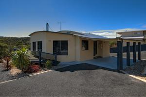a small house with a porch and a driveway at Mayakitana ~ Overlooking the golf course in Coles Bay