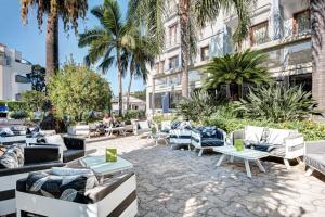 a patio with couches and tables and palm trees at Hotel Caravel in Sant'Agnello