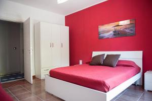 ein rotes Schlafzimmer mit einem Bett und einer roten Wand in der Unterkunft Be and Be in Montesano sulla Marcellana