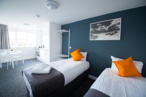a bedroom with two beds with orange pillows and a table at Fox Street Studios in Liverpool