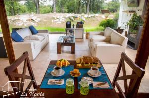 una sala de estar con una mesa con comida. en Posada La Rosita, en Santa Rosa de Calamuchita