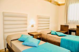 een kamer met 2 bedden en blauwe kussens bij BHB Hotel in Manduria