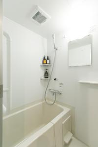 a white bathroom with a tub and a shower at Laon Inn Gion Nawate in Kyoto