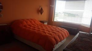 an orange bed in a room with a window at Edificio Maritim Algarrobo in Algarrobo