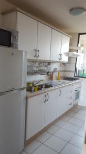 a kitchen with white cabinets and a white refrigerator at Edificio Maritim Algarrobo in Algarrobo