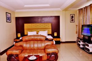 a bedroom with a bed and a couch and a television at Sweet Spirit Hotel and Suites Danag - Port Harcourt in Port Harcourt