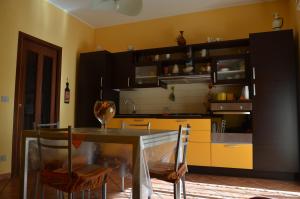 una cucina con tavolo, sedie e armadi gialli di Enzo's Homestay a Gaggi