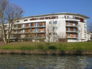 - un grand bâtiment à côté d'une étendue d'eau dans l'établissement Beau Rivage Appart', à Souffelweyersheim