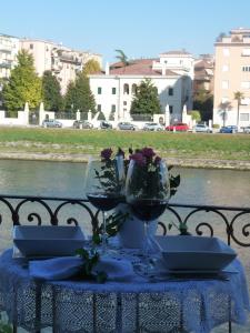 Casa Archi - Balcone sul Fiume في فيرونا: طاولة مع كأسين من النبيذ والزهور عليها