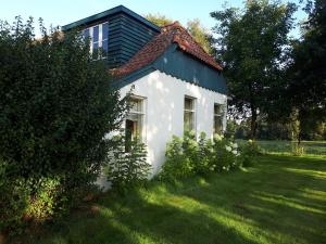 una pequeña casa blanca con techo verde en Voorhuis, en Eelde-Paterswolde
