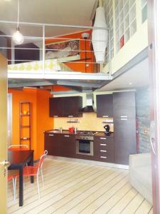 ミラノにあるNolo Loft in Milanのオレンジ色の壁と茶色のキャビネットが備わるキッチン