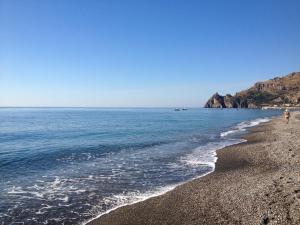 a person walking on a beach near the water at Camping La Focetta Sicula in SantʼAlessio Siculo