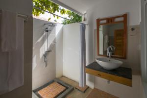 a bathroom with a sink and a shower with a mirror at Holiday Garden Rasdhoo in Rasdu