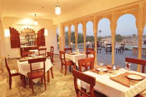 un restaurante con mesas y sillas blancas y un balcón en Deogarh Mahal, en Devgarh
