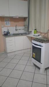 a kitchen with white cabinets and a stove top oven at Home Sweet Home Flats in Brasilia