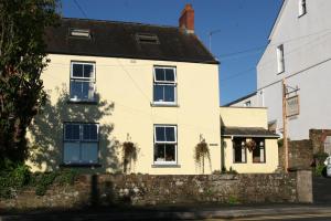 a white house with a stone wall at Nythfa Guest House in Saundersfoot