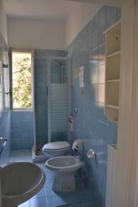 a blue tiled bathroom with two sinks and a toilet at Bed & Breakfast A Casa Mia in Bergamo