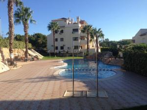 a swimming pool with palm trees and a building at Casa Lovia in Orihuela Costa