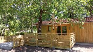 a wooden house with a fence and a tree at La Grange et Le Nid in Biscarrosse