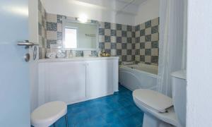 a bathroom with a toilet and a sink and a tub at Kastro Suites in Fira