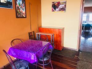 Una mesa morada en una habitación con una mesa y sillas. en Hostal Pachamama Lodge, en Cuenca