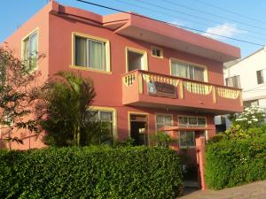a pink house with a balcony and bushes at Hostal Terito in Puerto Baquerizo Moreno
