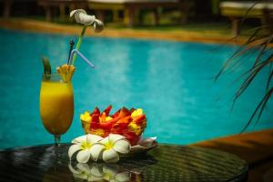 a drink on a table with a bowl of fruit and a plate of flowers at Papa Jolly Eco Resort-Near Morjim Beach in Morjim