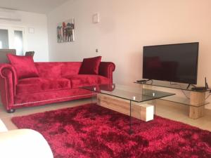 sala de estar con sofá rojo y TV en Marina Golf Apartments, en San Miguel de Abona