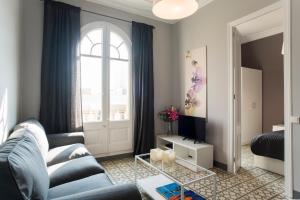 a living room with a blue couch and a window at Barcelonaguest in Barcelona