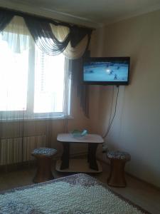 バルナウルにあるApartment on Sergeya Uskova 3のテーブルと壁掛けテレビ付きの部屋