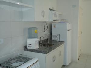 cocina con fregadero y nevera blanca en Edifício NEO 1, en Maceió