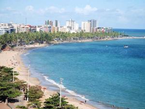 Una vista de una playa con una ciudad al fondo. en Edifício NEO 1, en Maceió