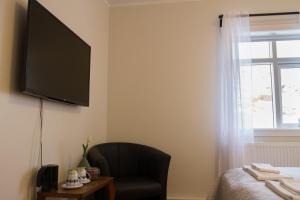 a bedroom with a chair and a television on the wall at Finna Hótel in Hólmavík