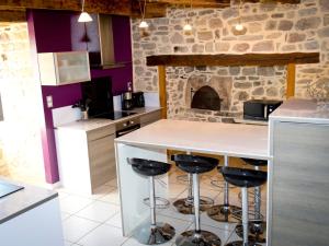 a kitchen with a counter and a stone fireplace at Le Crochet de Pervenche in Recoules-Prévinquières