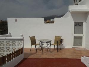 eine Terrasse mit einem Tisch und Stühlen an einer weißen Wand in der Unterkunft Casa Maye in La Cisnera