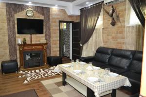 a living room with a black leather couch and a fireplace at Gostinitsa Grand in Qyzylorda