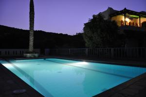 a swimming pool at night with a lighthouse in the background at Athina Villas in Istro