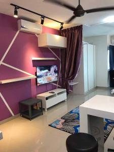 ein Wohnzimmer mit einem TV und einer lila Wand in der Unterkunft Galleria Equine Park in Seri Kembangan