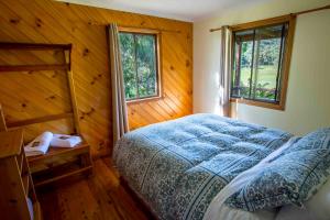 ein Schlafzimmer mit einem Bett und zwei Fenstern in der Unterkunft Wisteria Cottage in Wyberba