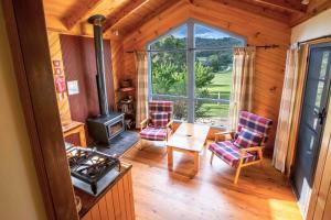 ein Wohnzimmer mit einem Herd und Stühlen in der Unterkunft Wisteria Cottage in Wyberba