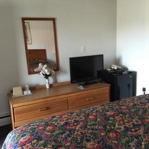 1 dormitorio con 1 cama y vestidor con TV en Valley Motel Pittsburgh, en Harmarville